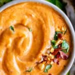 thai peanut sauce recipe in a bowl sprinkled with cilantro, dried chili, and cucumbers on the side