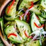 thai cucumber salad with cucumbers, shallots, red pepper, and cilantro in a wooden bowl