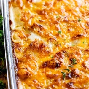 scalloped potatoes in a clear glass pan sprinkled with parsley