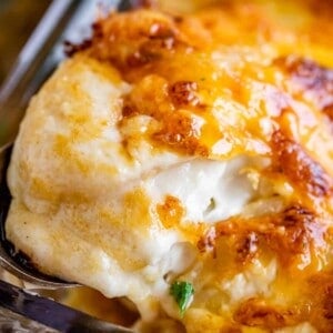 scalloped potatoes with cheese topping being lifted out of the pan with a spoon