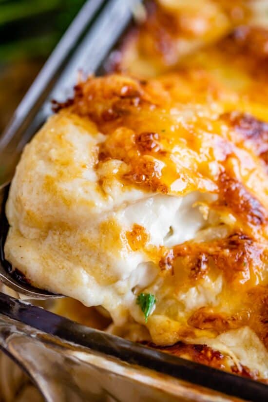scalloped potatoes with cheese topping being lifted out of the pan with a spoon