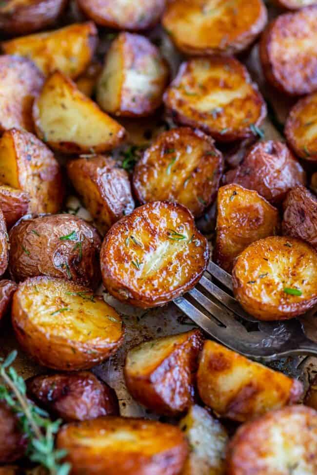 garlic red roasted potatoes with fresh herbs on a sheet pan with a fork.