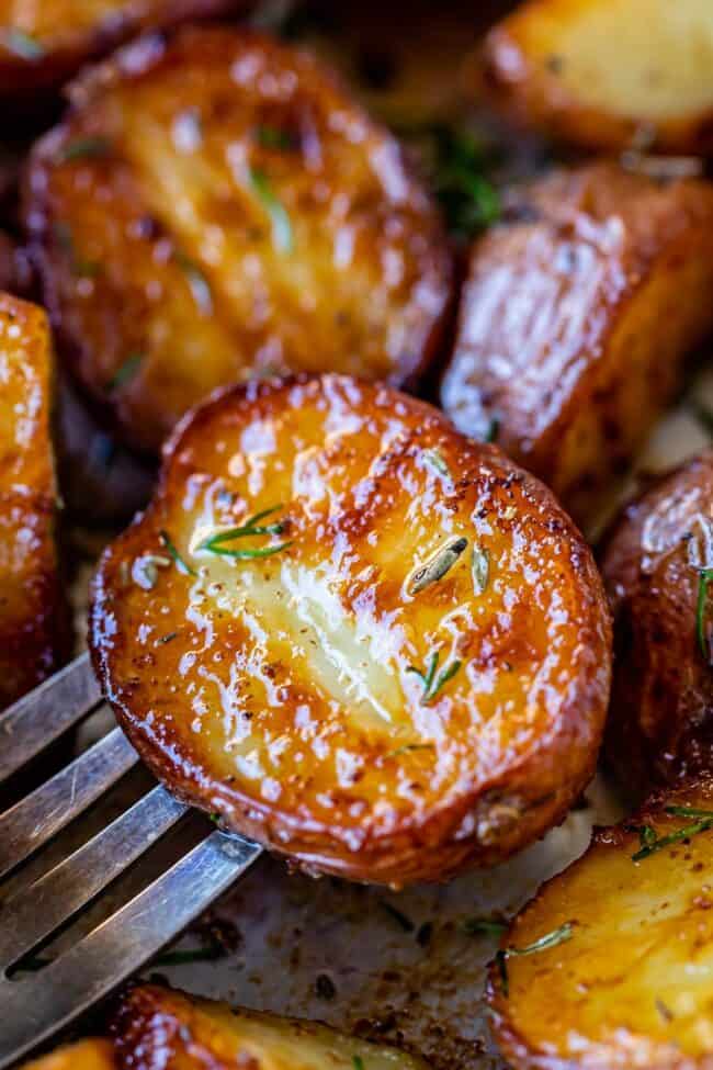 roasted red potatoes on a fork sprinkled with herbs.