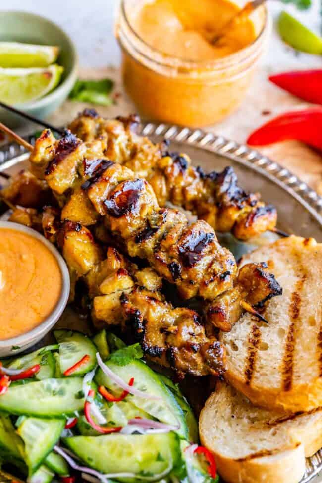 chicken satay skewers with grilled bread, cucumber salad, and peanut sauce.