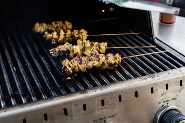marinated chicken thighs on wooden skewers on the grill.