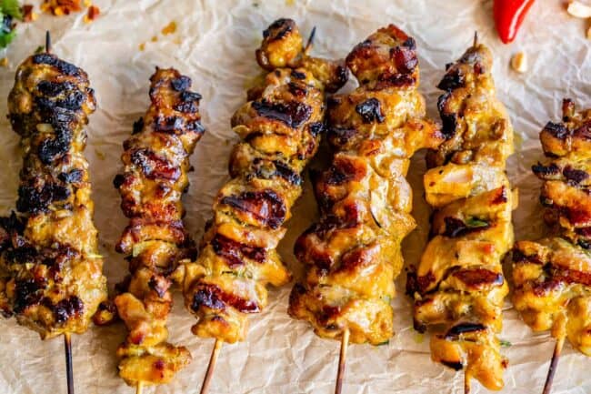 marinated chicken thighs on wooden skewers lined up in a row.