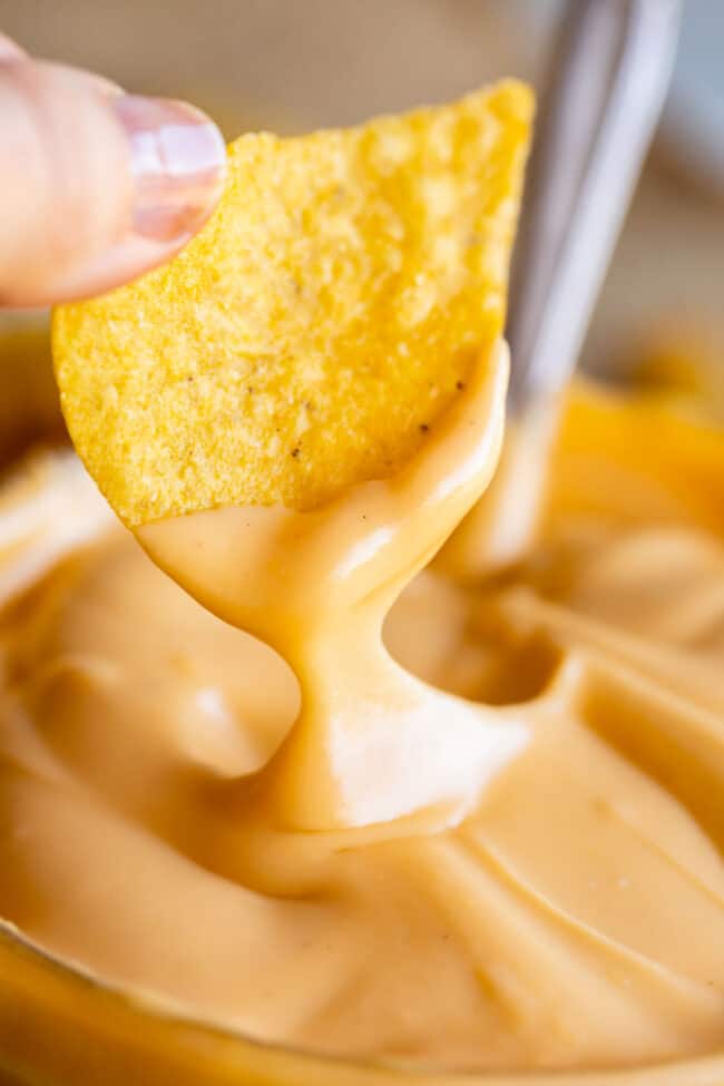 a tortilla lifting cheese sauce from a bowl