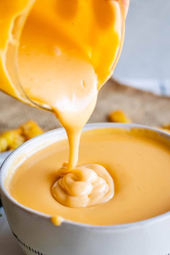 shake shack cheese sauce being poured into a white bowl.