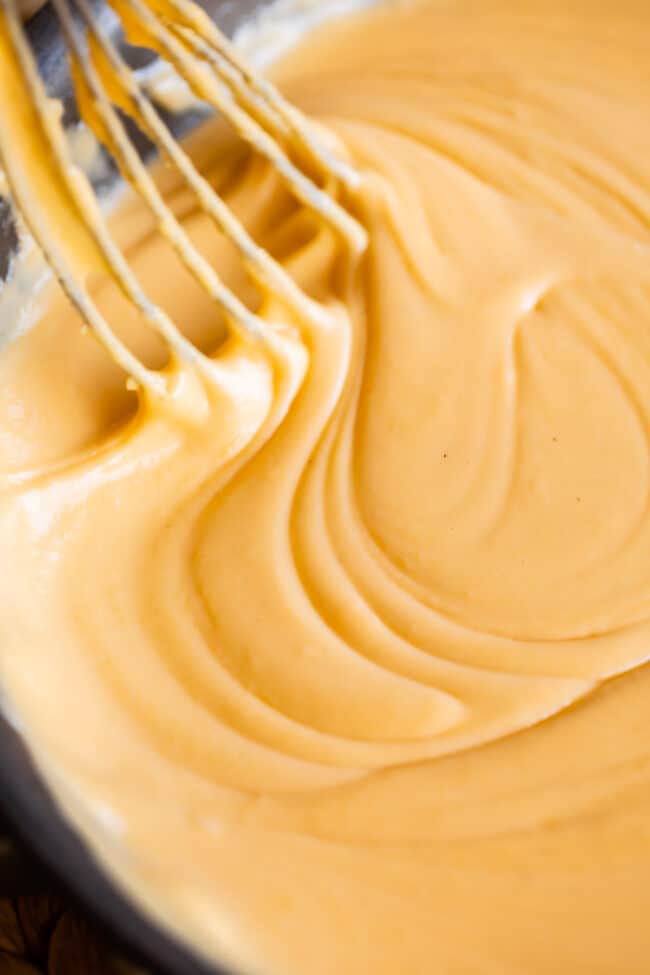 Swirling a whisk through a pan of cheese sauce