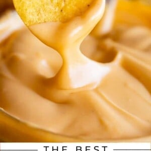 a hand dipping a tortilla chip into shack shack cheese sauce