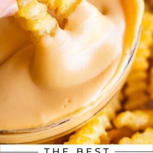 dipping two fries into a bowl of easy homemade cheese sauce