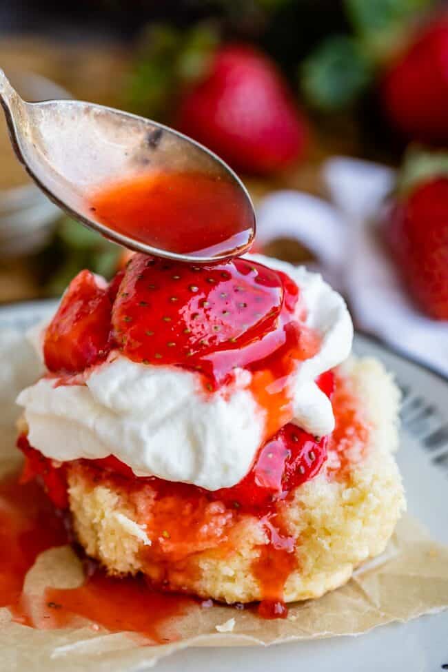 spooning juice over the top of strawberry shortcake stack.