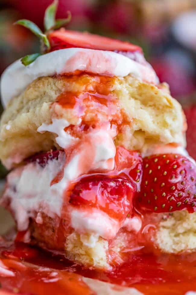 strawberry shortcake biscuits stacked together with strawberries and whipped cream.