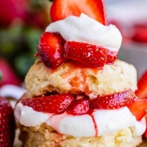 strawberry shortcake biscuits stacked together with strawberries and whipped cream