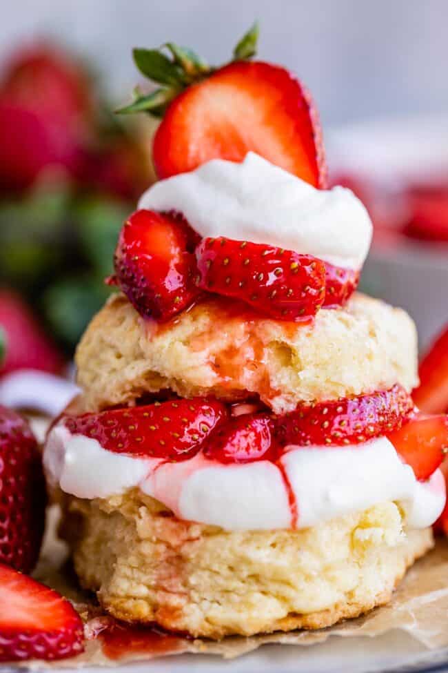 strawberry shortcake biscuits stacked together with strawberries and whipped cream.