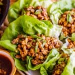 chicken lettuce wraps on a plate near dipping sauce.
