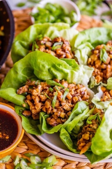 chicken lettuce wraps on a plate near dipping sauce.