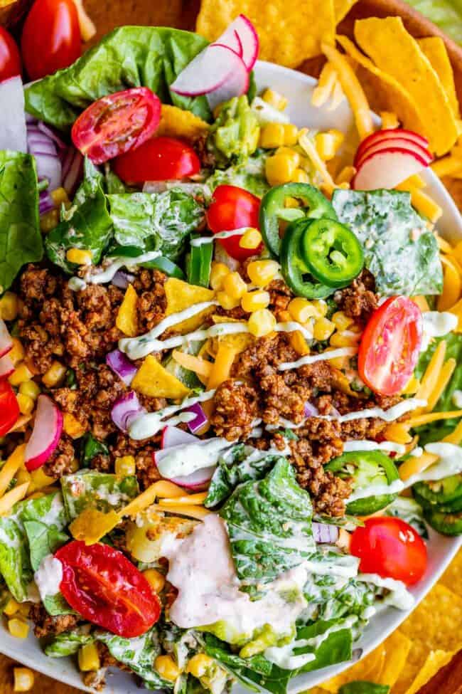 best taco salad mixed together on a plate, surrounded by chips