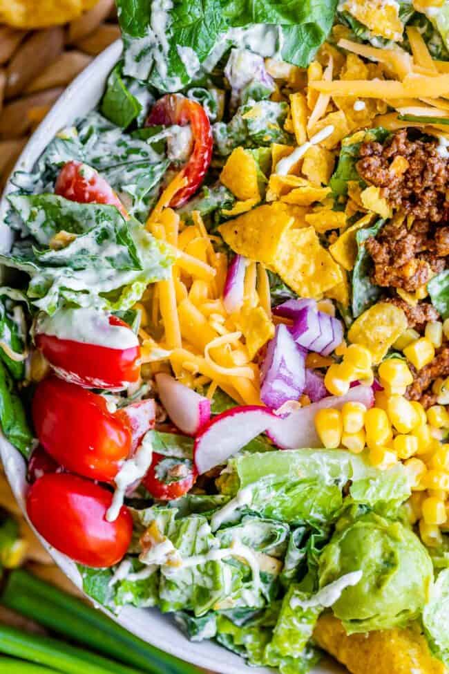 taco salad in a bowl with cheese and cherry tomatoes.