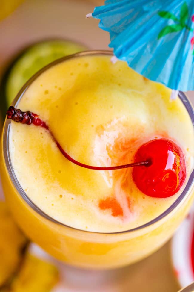 close up shot of virgin pina colada with a maraschino cherry and an umbrella.