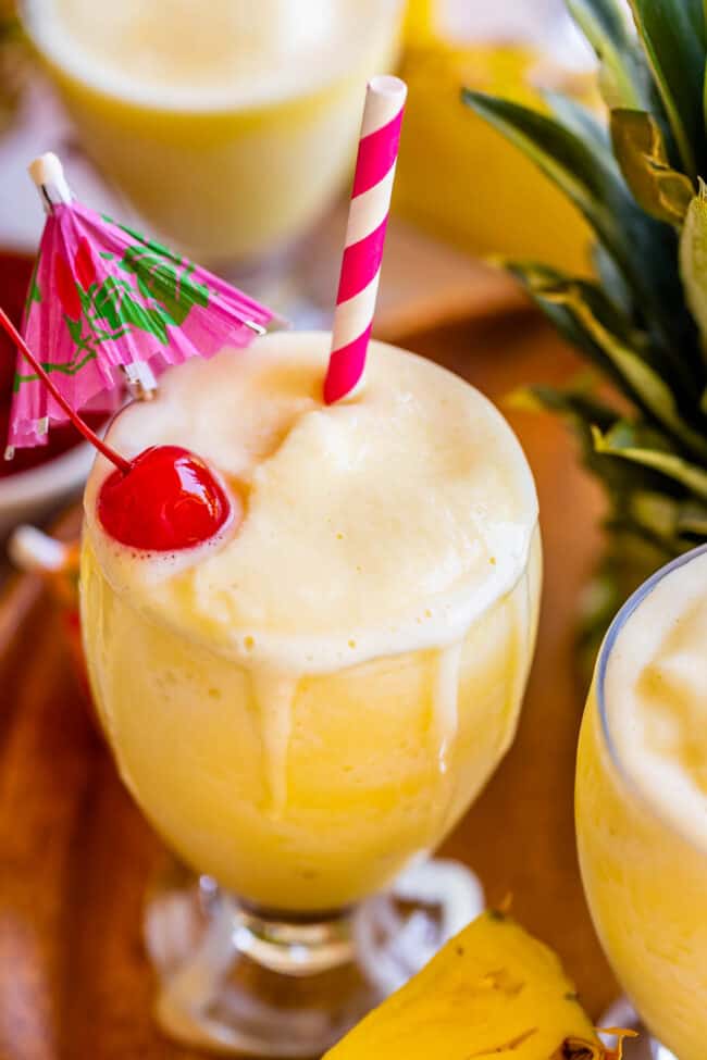 virgin pina colada with cherry, pink umbrella, and striped straw, dripping down the sides of the glass.