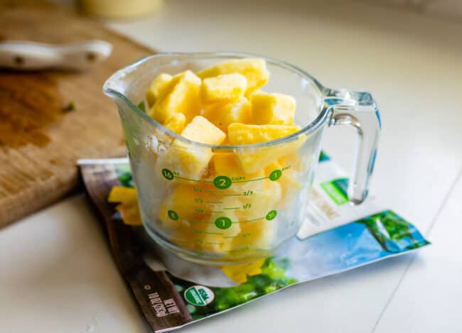 frozen pineapple chunks in a glass measuring cup.