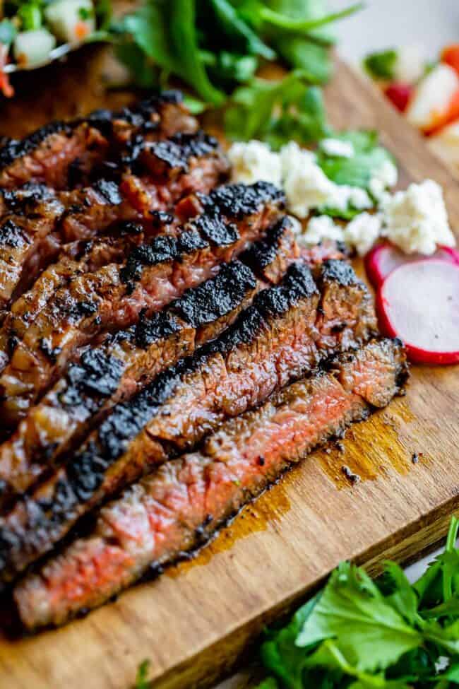 carne asada meat sliced against the grain on a wooden cutting board.