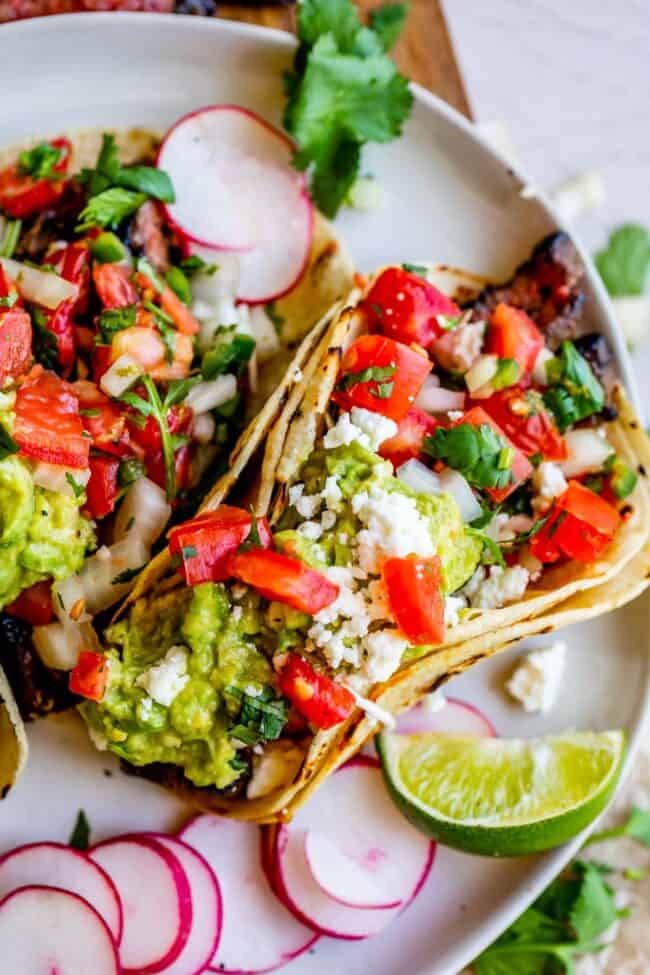 carne asada, guacamole, and pico de gallo in a taco, on a plate with radishes.