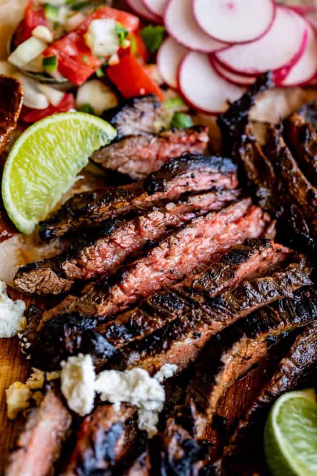 sliced carne asada with limes and pico de gallo