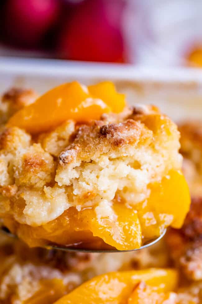 lifting peach cobbler out of the pan on a spoon