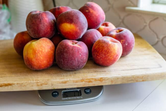 5 pounds of peaches on a cutting board on a scale.