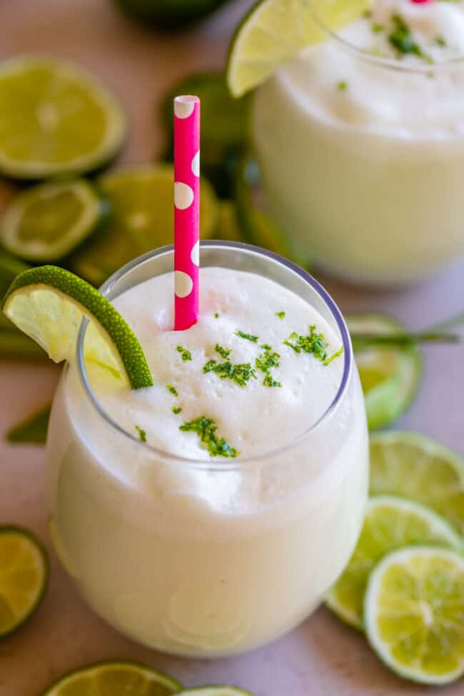 Brazilian Lemonade in a glass with lime zest on top and a pink polka dot straw.