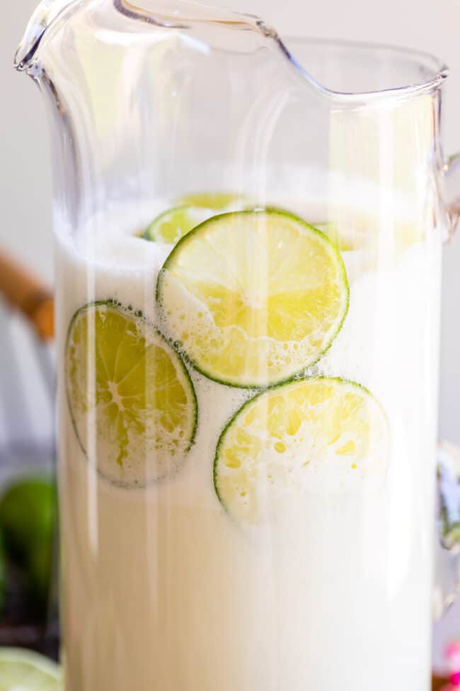 Brazilian lemonade in a pitcher with sliced limes.