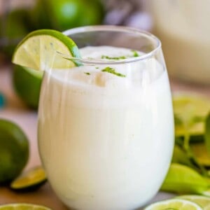 braziilian limeade recipe in a stemless wine glass with lime wedges