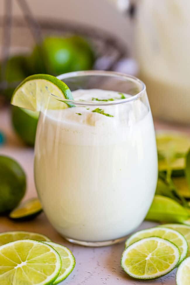 braziilian limeade recipe in a stemless wine glass with lime wedges.