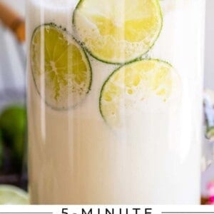 Brazilian Limeade in a clear glass pitcher with lime garnish