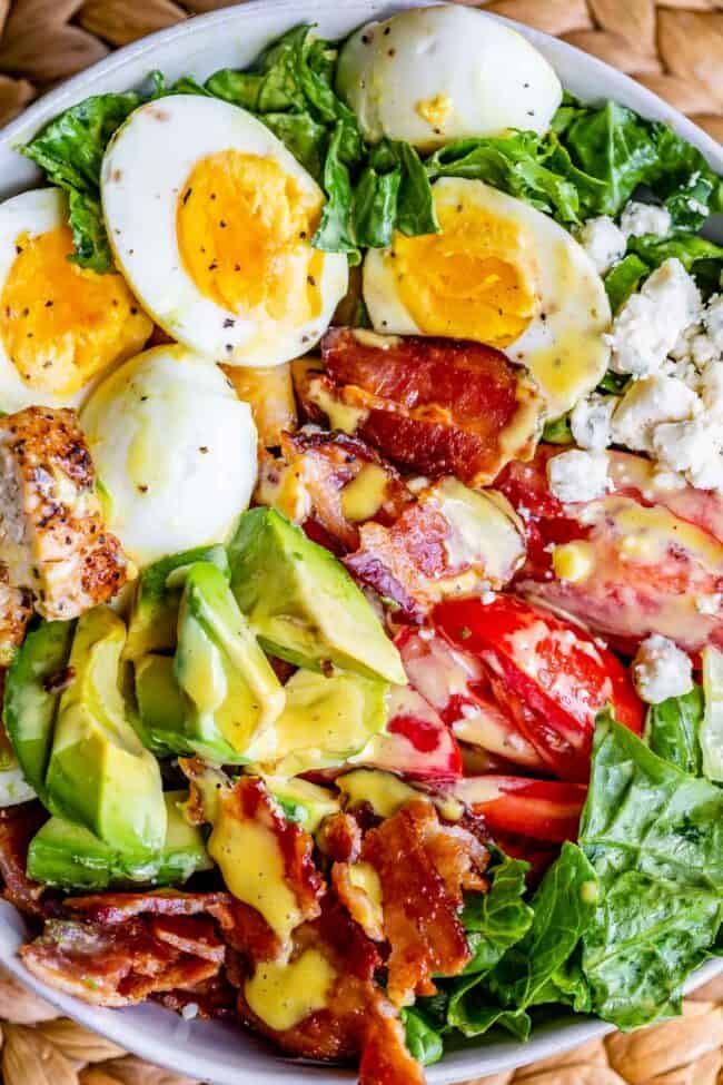cobb salad recipe in a white bowl with dressing on top