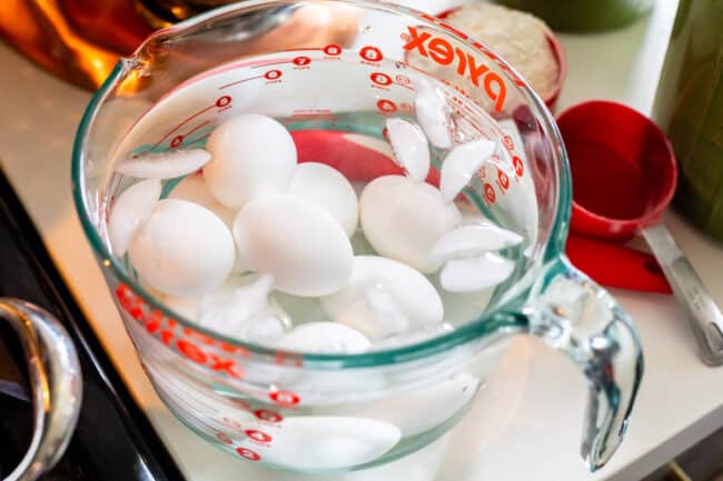 boiled eggs cooling in an ice bath on a white kitchen counter