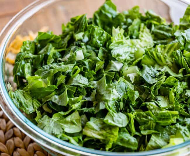 chopped romaine lettuce and green onions in a large clear bowl.