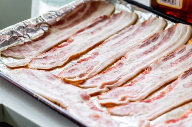 raw bacon on a foil-lined baking sheet