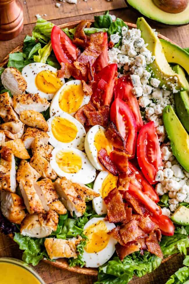 best cobb salad, with ingredients lined up across a wooden plate.