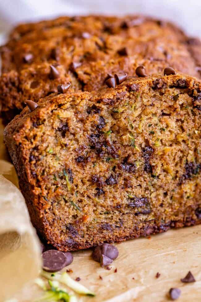 closeup of a slice of moist zucchini bread with a full loaf in the background.