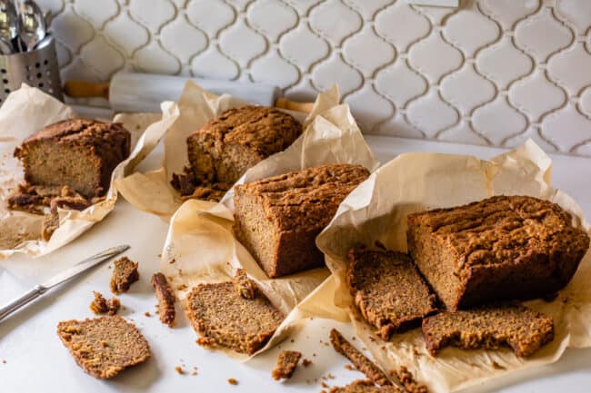 four loaves of zucchini bread on a counter with slices cut off.