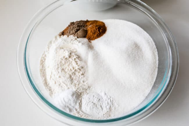 a glass bowl with flour and other dry ingredients showing how to make zucchini bread.