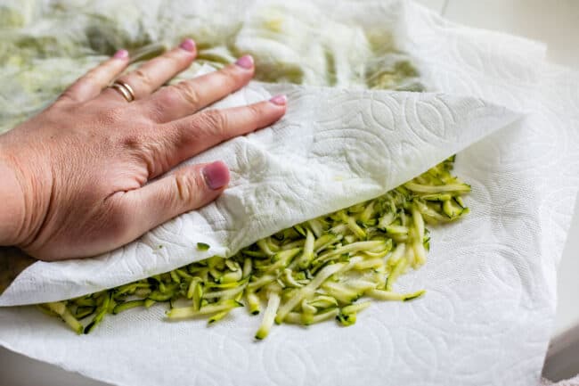 blotting shredded zucchini with paper towels.