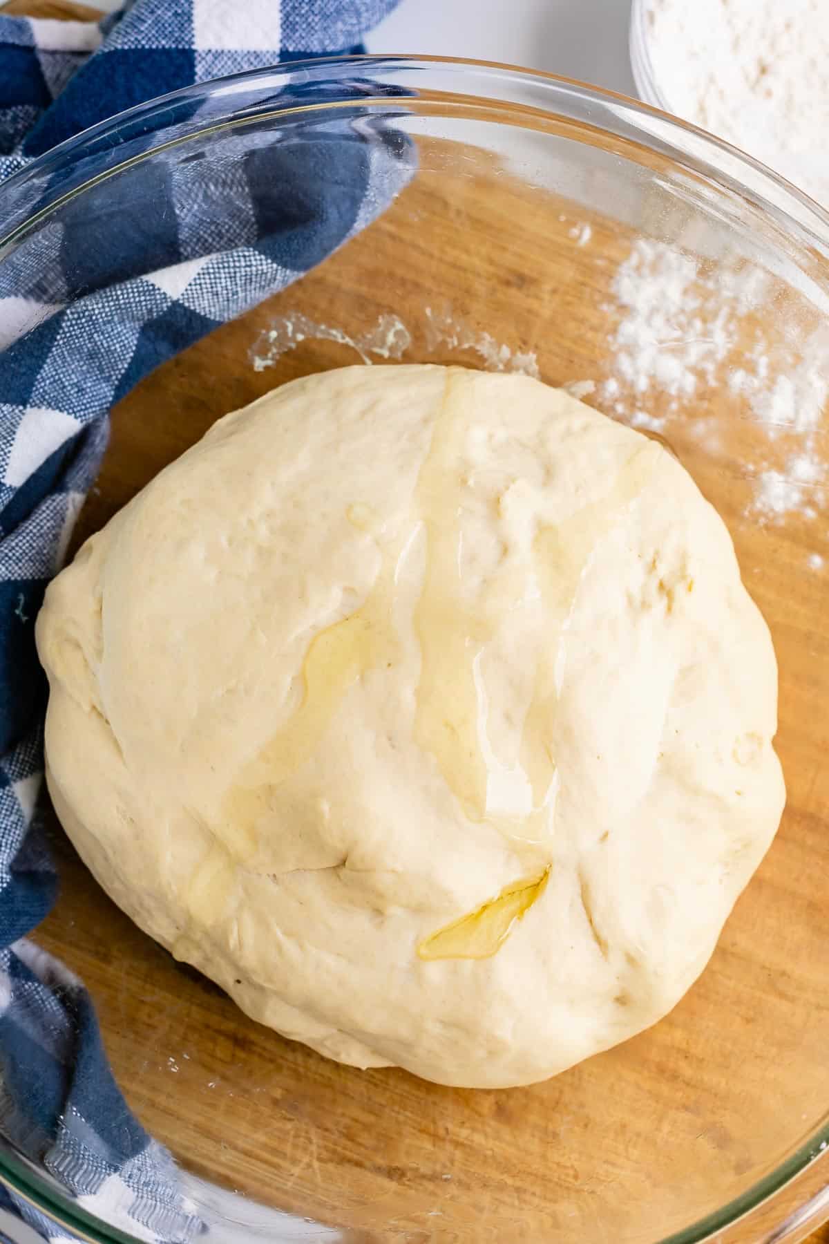 easy pizza dough recipe in a glass bowl with blue napkin