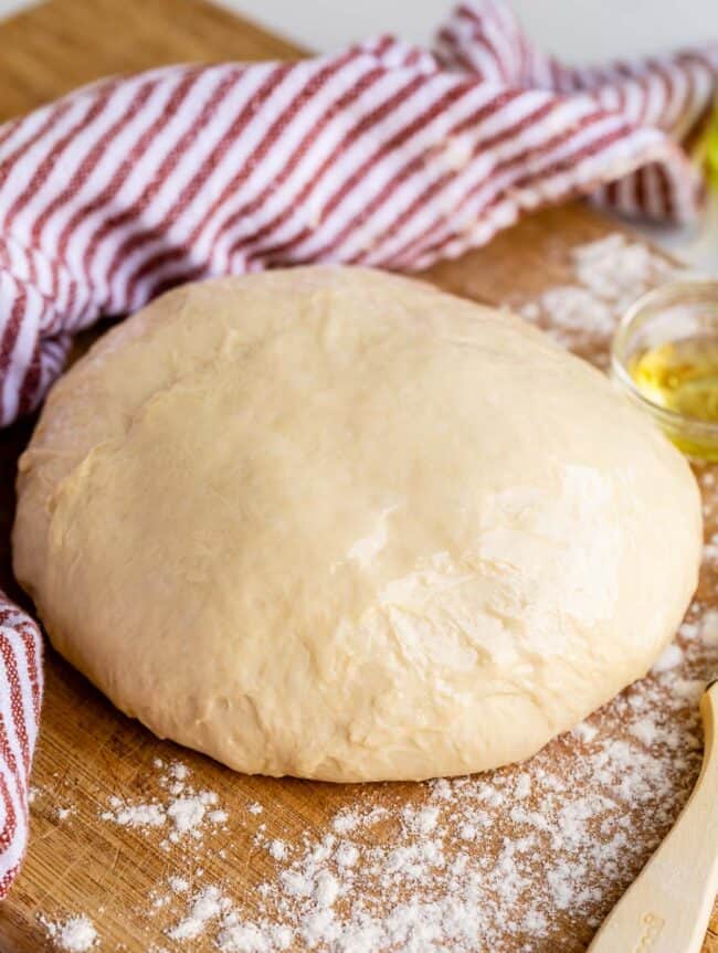 quick pizza dough on a cutting board with rust colored napkin.