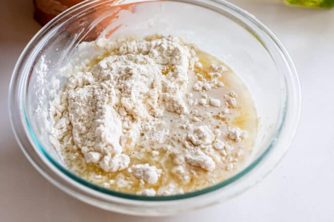 flour added to a bowl of yeast and water.