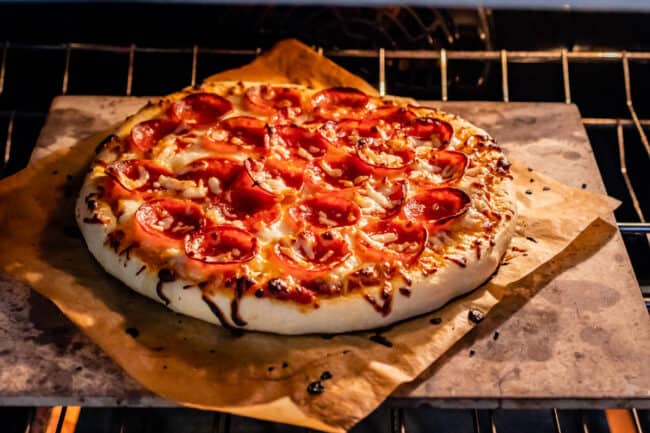 pizza baking in an oven on a pizza stone
