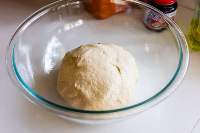 pizza dough in a glass bowl on a counter